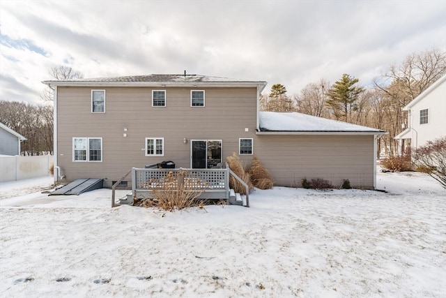 snow covered rear of property with a deck