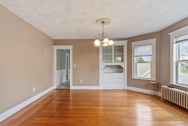 49-51 Fairmount Ave, Somerville, MA 02144 - unfurnished dining area featuring radiator, light wood-style flooring, a chandelier, and baseboards