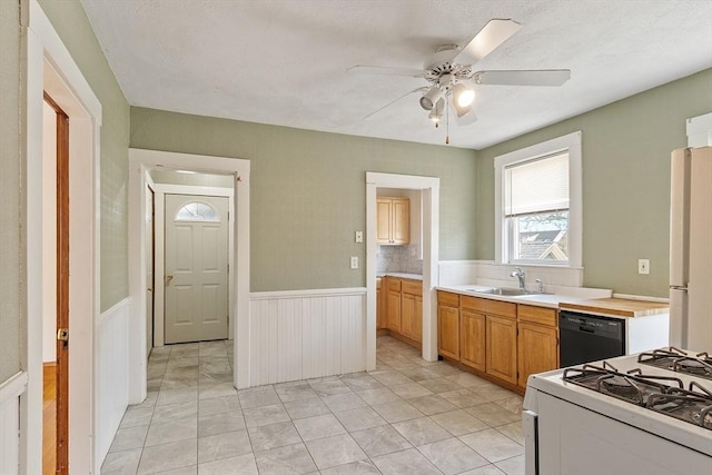 49-51 Fairmount Ave, Somerville, MA 02144 - kitchen featuring dishwasher, a sink, white range with gas cooktop, a wainscoted wall, and freestanding refrigerator