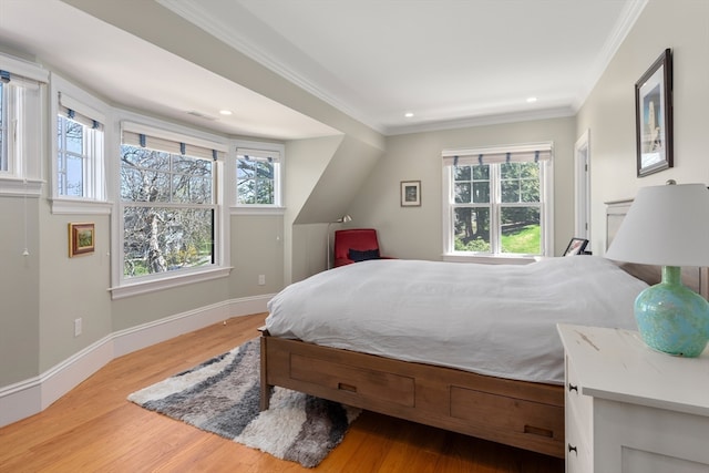 bedroom featuring light hardwood / wood-style flooring, ornamental molding, and multiple windows