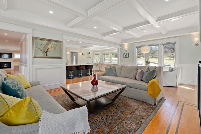 living room with light wood-type flooring, coffered ceiling, beamed ceiling, and ornamental molding