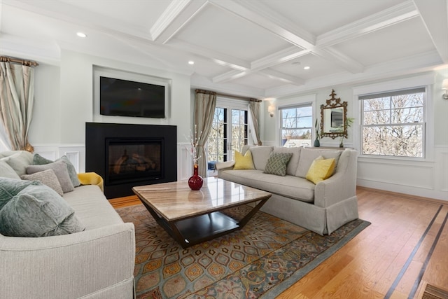 living room with ornamental molding, beamed ceiling, light hardwood / wood-style flooring, and coffered ceiling