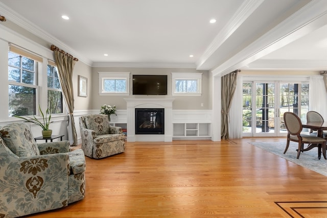 living area featuring crown molding, a healthy amount of sunlight, and light hardwood / wood-style flooring