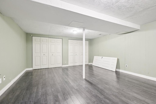 basement featuring a textured ceiling and dark hardwood / wood-style floors