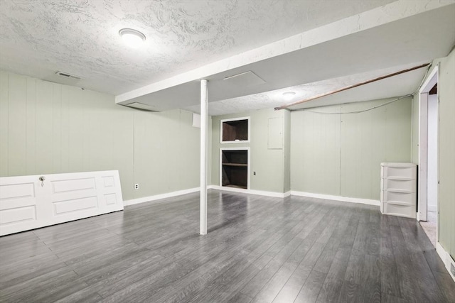 basement with a textured ceiling and dark hardwood / wood-style floors