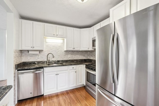 kitchen with light wood-type flooring, appliances with stainless steel finishes, white cabinetry, and sink