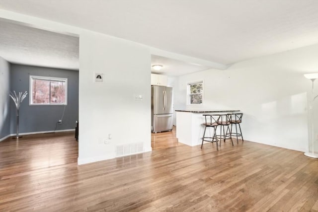 empty room with beam ceiling, a wealth of natural light, and hardwood / wood-style floors