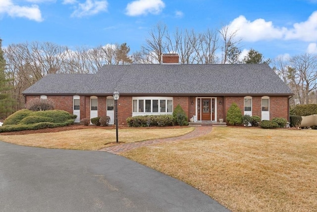 single story home with brick siding, a chimney, a front lawn, and a shingled roof