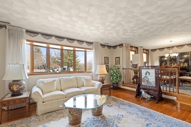 living area featuring a notable chandelier, wood finished floors, and a textured ceiling