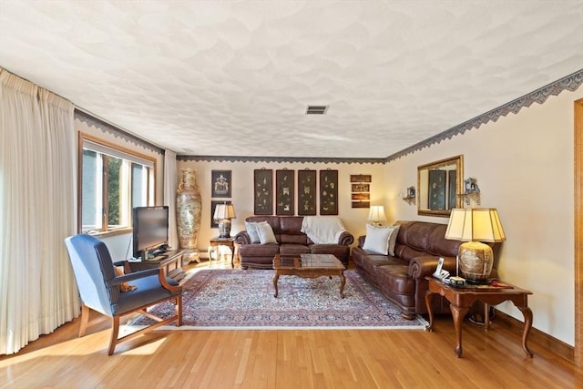 living room with wood finished floors, visible vents, and a textured ceiling