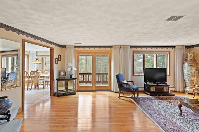 living area featuring visible vents, plenty of natural light, and light wood-style flooring