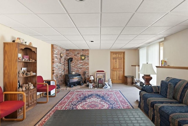 living room featuring a drop ceiling, carpet, and a wood stove