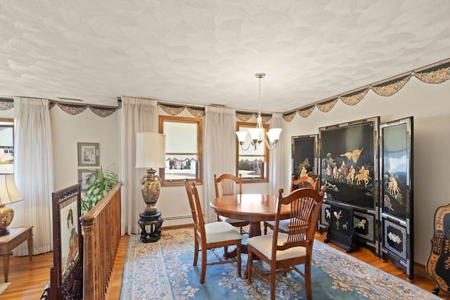 dining space featuring a notable chandelier, a textured ceiling, and wood finished floors