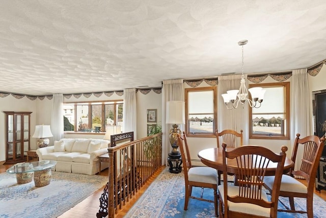 dining space with wood finished floors, a textured ceiling, and a chandelier