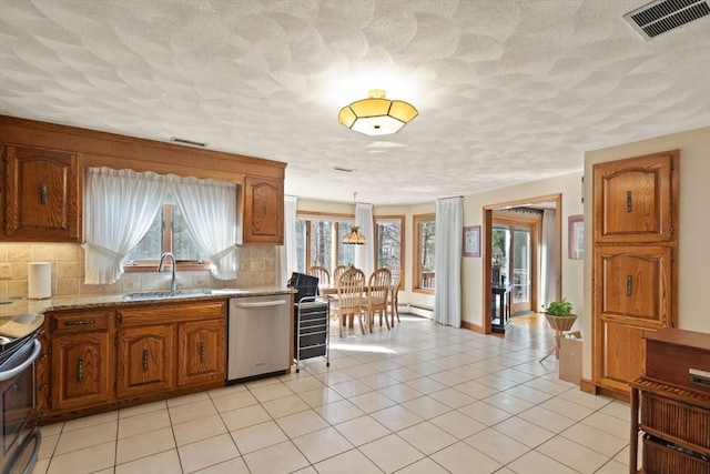 kitchen featuring brown cabinetry, visible vents, a sink, stainless steel appliances, and tasteful backsplash