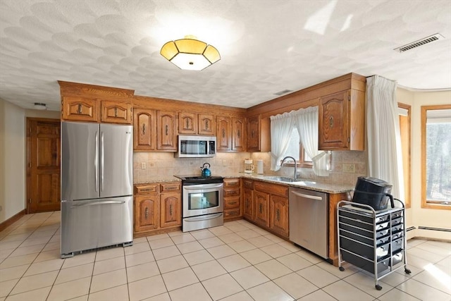 kitchen featuring a sink, brown cabinetry, visible vents, and stainless steel appliances