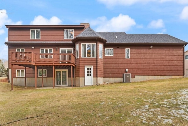 rear view of property with central AC unit, a lawn, a deck, and a shingled roof