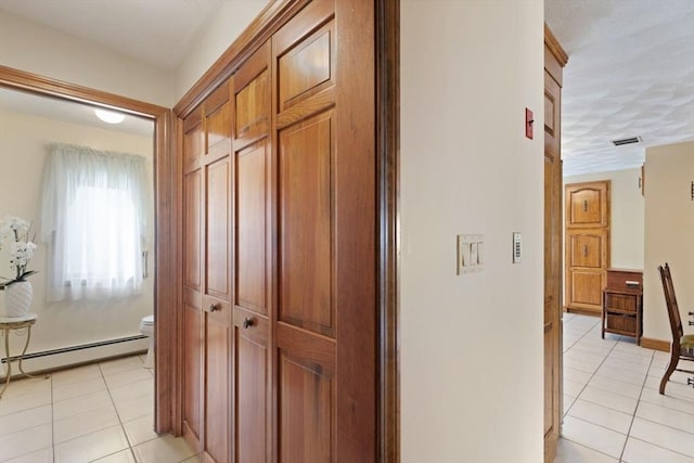 corridor with light tile patterned floors, visible vents, and baseboard heating