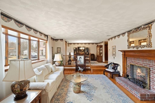 living room with a brick fireplace, wood finished floors, and a textured ceiling