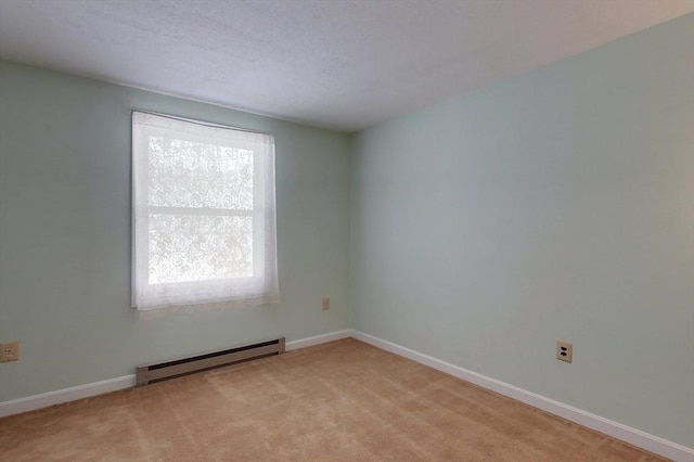 empty room featuring baseboards, baseboard heating, and light colored carpet