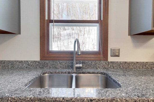 interior details featuring a sink and dark stone countertops