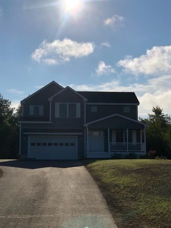 view of front of house with a porch, a garage, and a front lawn