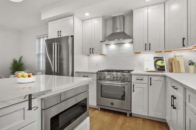 140 Main St Unit E, Amesbury, MA 01913 - kitchen featuring wall chimney exhaust hood, high end appliances, light countertops, backsplash, and white cabinetry