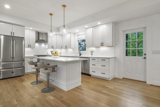 140 Main St Unit E, Amesbury, MA 01913 - kitchen with appliances with stainless steel finishes, wall chimney exhaust hood, light wood finished floors, backsplash, and recessed lighting