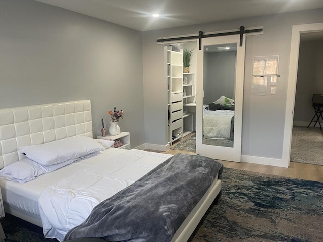200 Manning St Unit 17C, Hudson, MA 01749 - bedroom featuring a barn door, wood finished floors, baseboards, and a walk in closet
