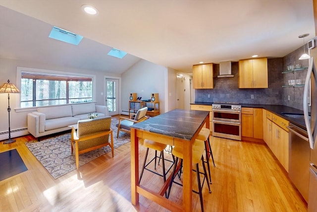 kitchen featuring double oven range, light wood-style floors, backsplash, dark countertops, and wall chimney exhaust hood