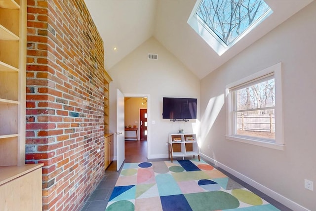 recreation room featuring baseboards, visible vents, a skylight, and high vaulted ceiling