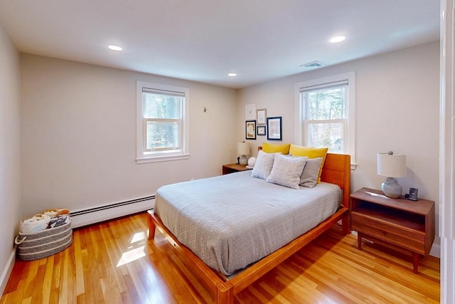 bedroom with recessed lighting, visible vents, baseboard heating, and light wood-style floors