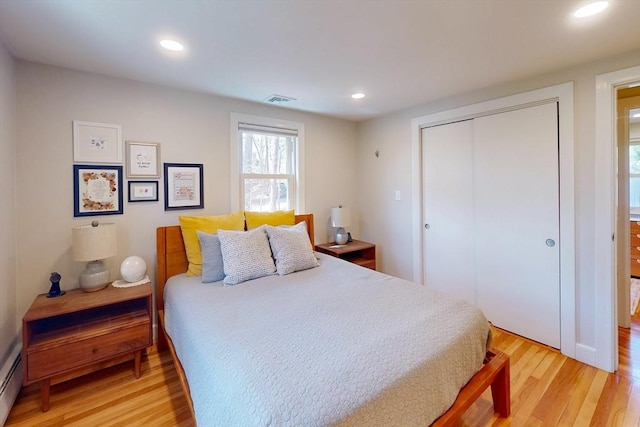 bedroom featuring a baseboard radiator, light wood-style floors, visible vents, a closet, and recessed lighting