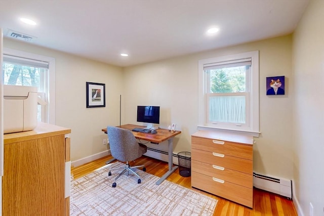 office space featuring a wealth of natural light, visible vents, light wood-type flooring, and a baseboard heating unit