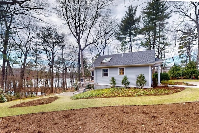 view of side of property with a yard and a shingled roof
