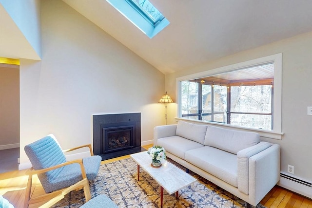 living room featuring a fireplace with flush hearth, lofted ceiling with skylight, baseboards, wood finished floors, and a baseboard radiator