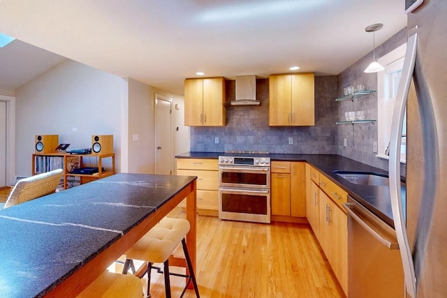 kitchen with stainless steel appliances, light wood-style floors, dark countertops, backsplash, and wall chimney exhaust hood