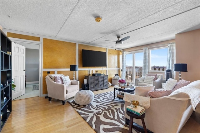 living area with a textured ceiling, a ceiling fan, and wood finished floors