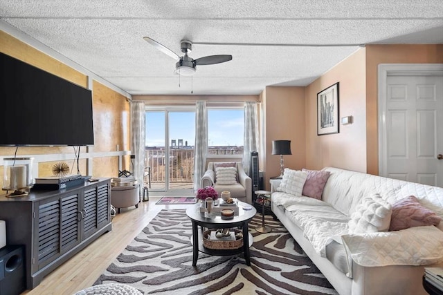 living room with a textured ceiling, light wood-style flooring, and a ceiling fan