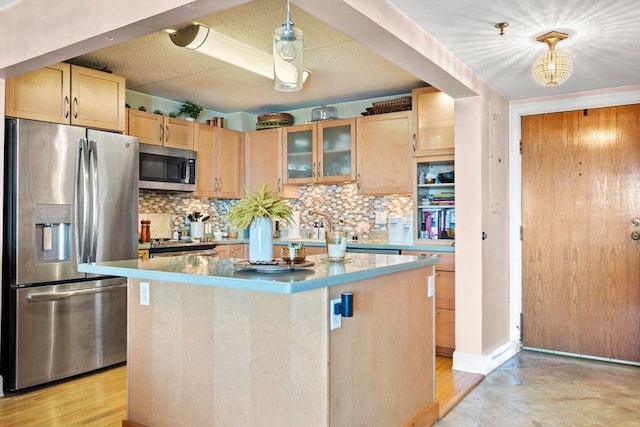 kitchen featuring light brown cabinets, stainless steel appliances, decorative backsplash, glass insert cabinets, and a center island