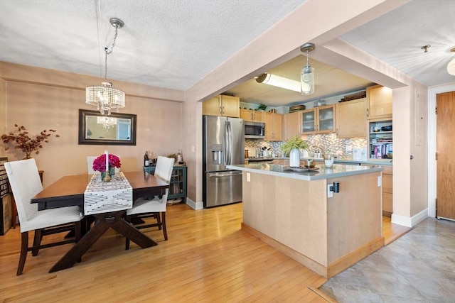 kitchen with tasteful backsplash, light wood finished floors, light brown cabinets, a kitchen island, and stainless steel appliances