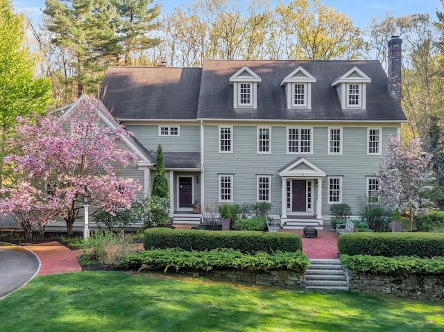 view of front facade featuring a chimney and a front lawn