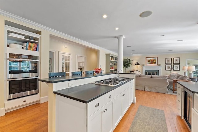 kitchen with a sink, stainless steel appliances, dark countertops, and ornate columns