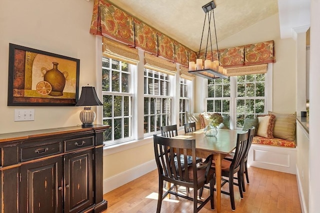 dining space with light wood finished floors, baseboards, and vaulted ceiling