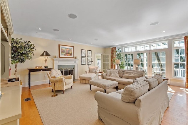 living room with a wealth of natural light, ornamental molding, a fireplace, and light wood finished floors