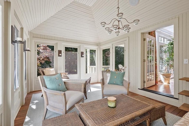 sunroom with plenty of natural light, lofted ceiling, and an inviting chandelier