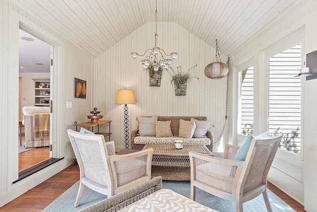 living area with a notable chandelier, a healthy amount of sunlight, wood finished floors, and vaulted ceiling