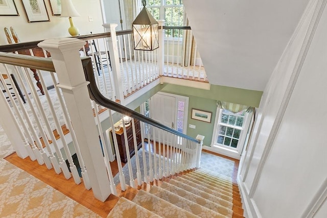 staircase featuring plenty of natural light, wood finished floors, and baseboards