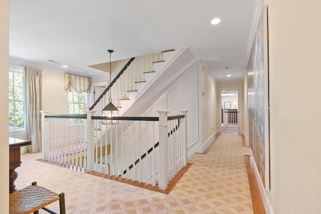 corridor with crown molding, recessed lighting, an upstairs landing, and light carpet