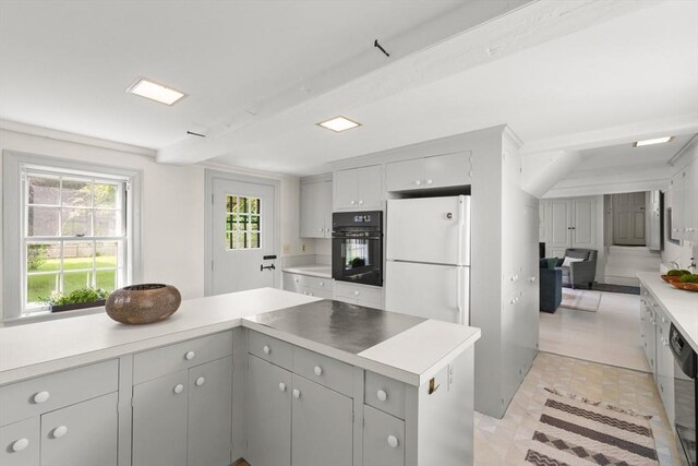 120 Court St, Dedham, MA 02026 - kitchen with black oven, gray cabinetry, freestanding refrigerator, light countertops, and stainless steel dishwasher